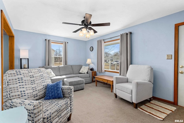 carpeted living area with baseboards and a ceiling fan