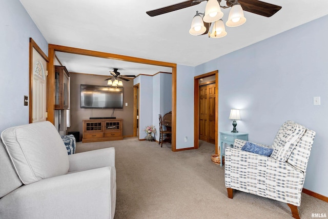 living area with carpet, baseboards, and ceiling fan