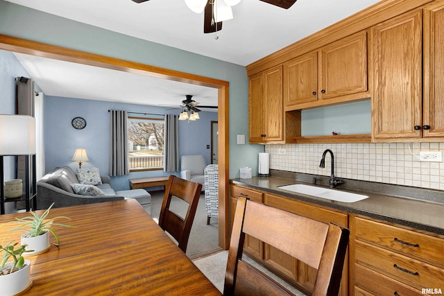 kitchen with open floor plan, brown cabinets, tasteful backsplash, and a sink