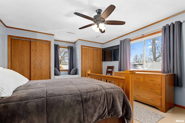 bedroom featuring baseboards, visible vents, ceiling fan, crown molding, and two closets