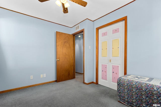 carpeted bedroom featuring crown molding, baseboards, visible vents, and ceiling fan