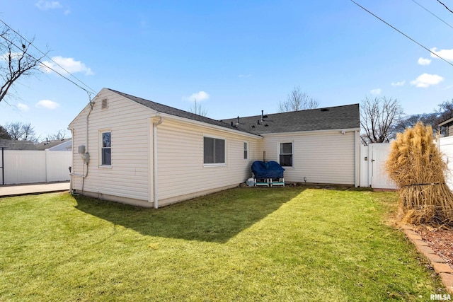 back of house featuring a gate, a yard, and fence