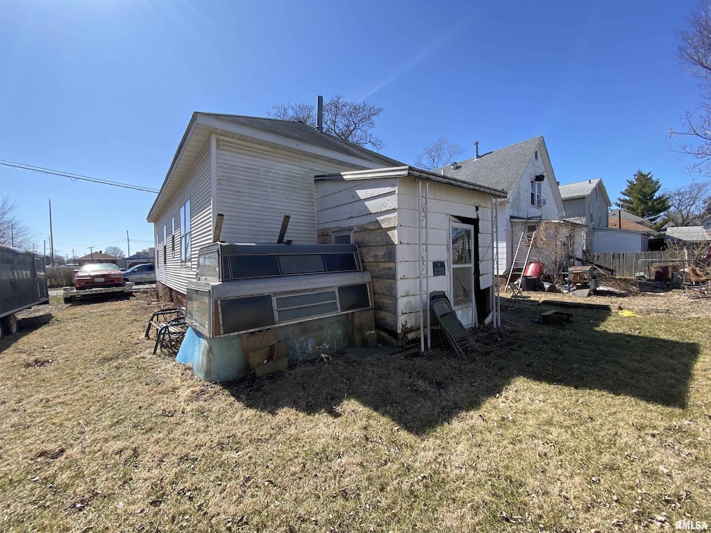 rear view of property featuring fence and a lawn