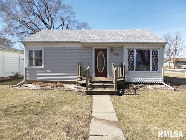 view of front of house featuring a front lawn and a shingled roof