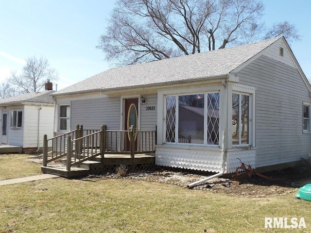 ranch-style home with a front yard and roof with shingles