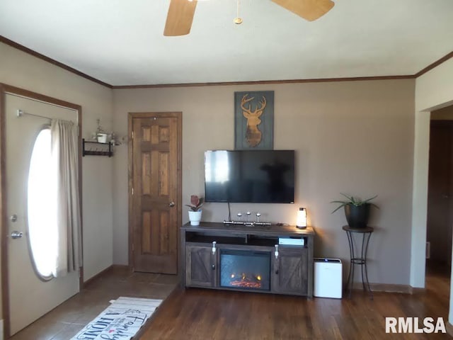 living area featuring baseboards, crown molding, ceiling fan, and wood finished floors