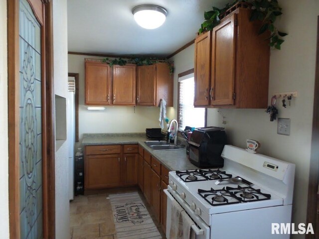 kitchen featuring brown cabinetry, light countertops, gas range gas stove, and a sink