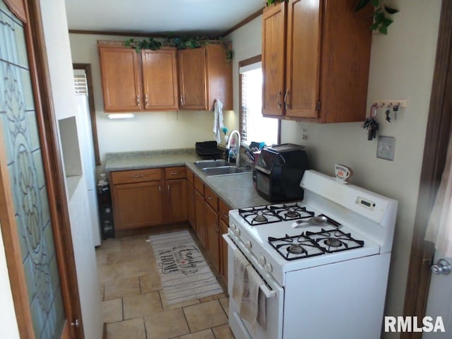 kitchen featuring a sink, white range with gas cooktop, brown cabinets, and light countertops