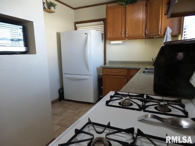 kitchen featuring a sink, brown cabinets, freestanding refrigerator, and ornamental molding