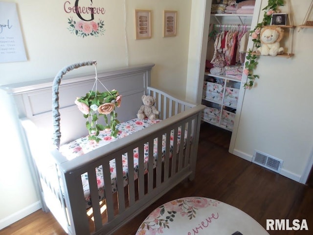 bedroom featuring a closet, visible vents, baseboards, and wood finished floors