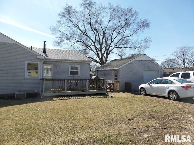 rear view of house featuring a yard, a garage, and a deck