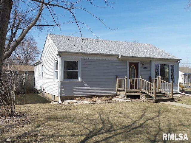 view of front of house featuring a front lawn, fence, and a shingled roof