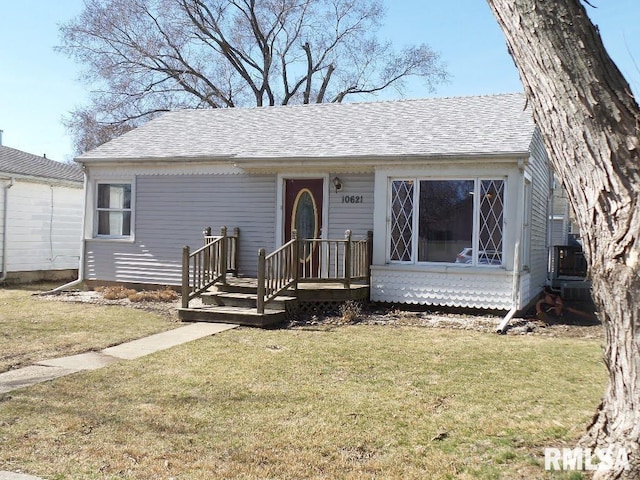 view of front of property featuring a front lawn and a shingled roof