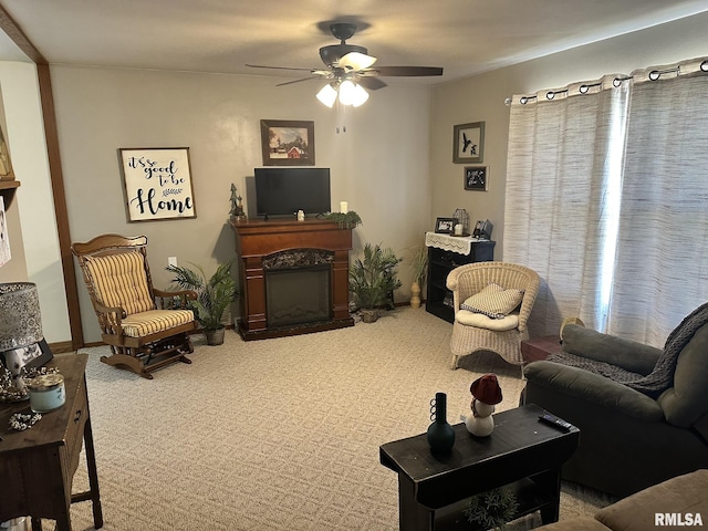 carpeted living area featuring ceiling fan and a fireplace