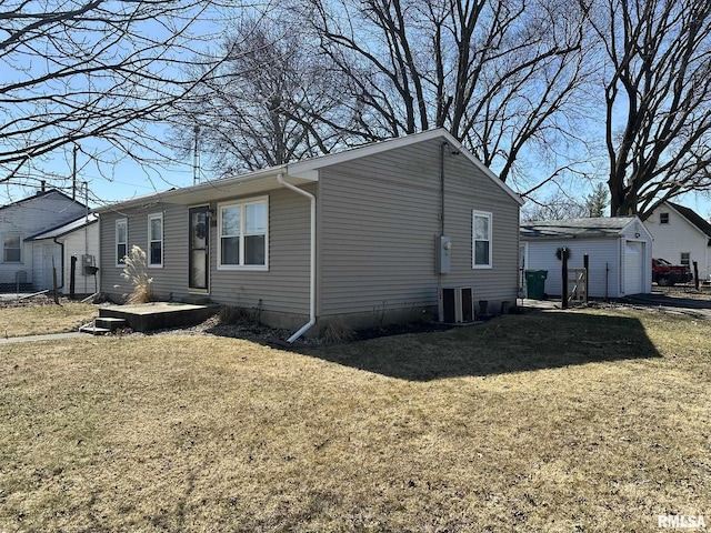 view of side of property with an outbuilding, a lawn, and central AC