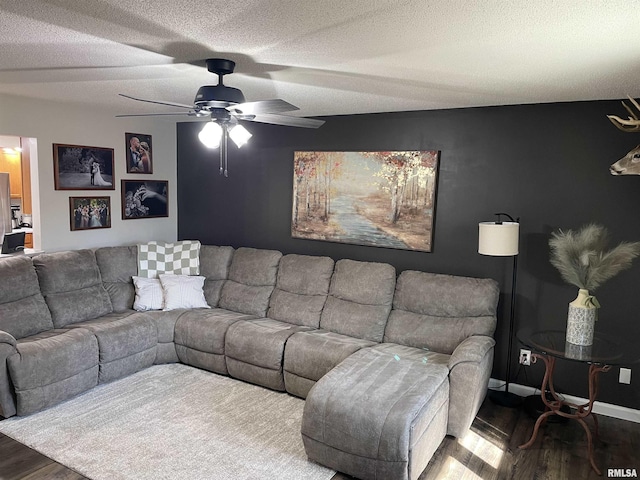 living area with ceiling fan, wood finished floors, baseboards, and a textured ceiling