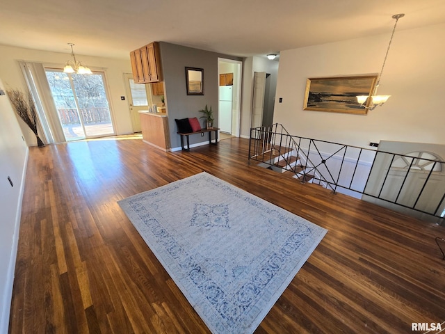 living area with dark wood-style floors, a notable chandelier, and baseboards