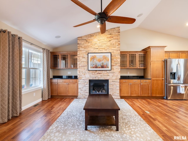 unfurnished living room featuring visible vents, baseboards, vaulted ceiling, light wood-style floors, and a ceiling fan