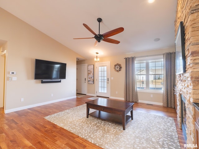 unfurnished living room featuring ceiling fan, baseboards, lofted ceiling, a fireplace, and wood finished floors