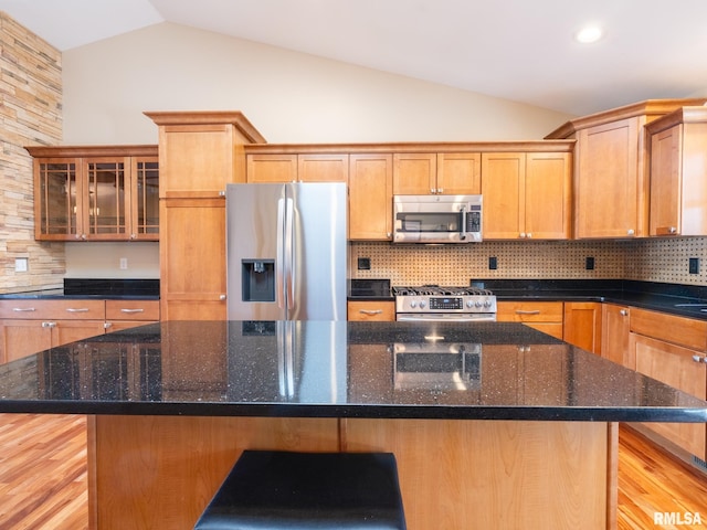 kitchen featuring lofted ceiling, backsplash, appliances with stainless steel finishes, and a center island