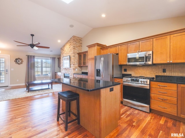 kitchen with a breakfast bar, light wood-style flooring, a center island, appliances with stainless steel finishes, and brown cabinetry