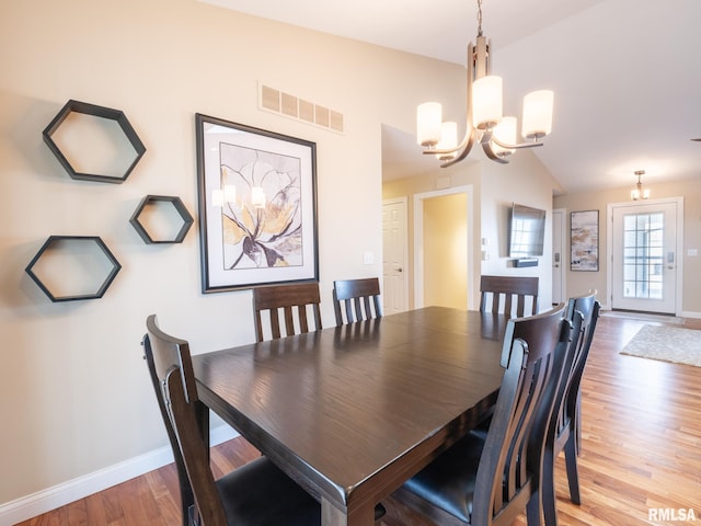 dining area with wood finished floors, baseboards, visible vents, lofted ceiling, and a chandelier