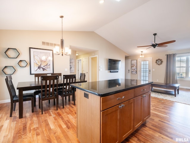 kitchen featuring visible vents, a center island, light wood-style floors, vaulted ceiling, and hanging light fixtures