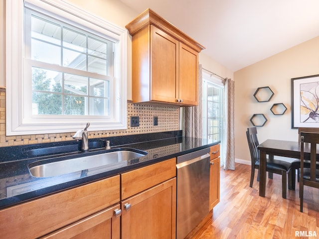 kitchen featuring a healthy amount of sunlight, dishwasher, vaulted ceiling, decorative backsplash, and a sink