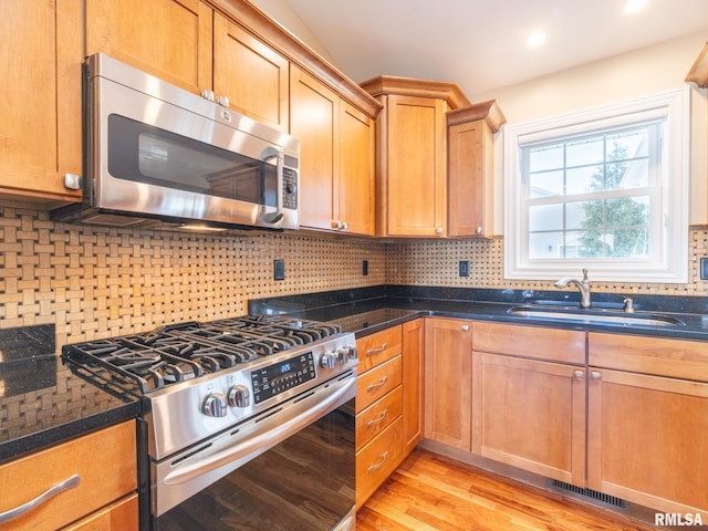 kitchen with visible vents, a sink, decorative backsplash, stainless steel appliances, and light wood-type flooring