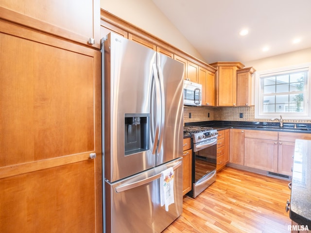 kitchen with tasteful backsplash, dark countertops, appliances with stainless steel finishes, and vaulted ceiling