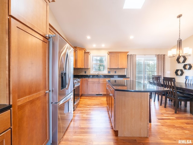 kitchen with backsplash, a center island, appliances with stainless steel finishes, light wood-style floors, and a sink