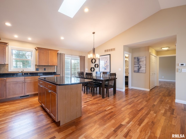 kitchen featuring a wealth of natural light, visible vents, a kitchen island, and dark countertops