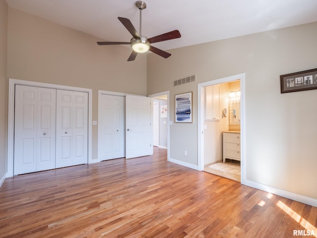 unfurnished bedroom with visible vents, baseboards, multiple closets, light wood-style floors, and ensuite bath