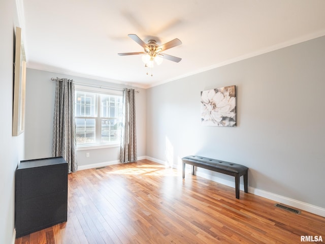 empty room featuring visible vents, crown molding, baseboards, and wood finished floors