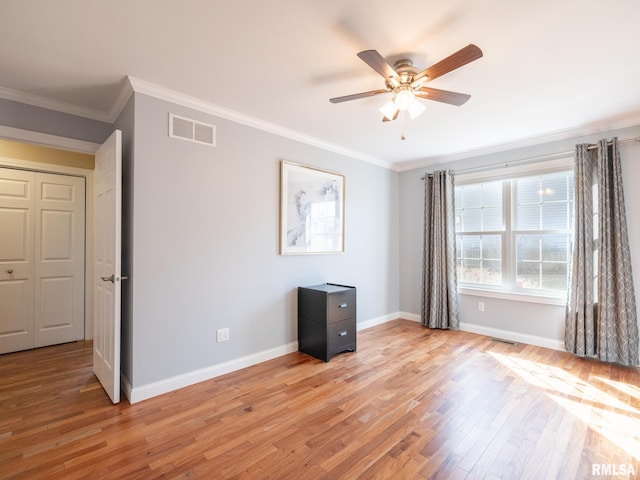 unfurnished bedroom featuring crown molding, light wood-style flooring, baseboards, and visible vents