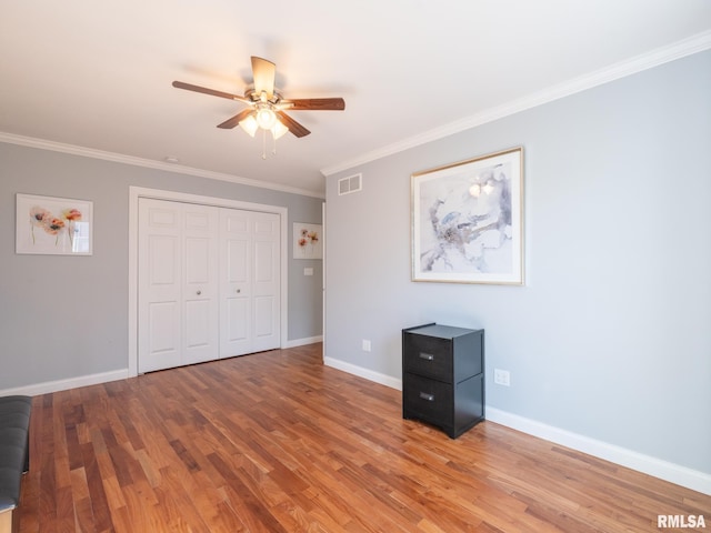 unfurnished bedroom with visible vents, crown molding, and wood finished floors