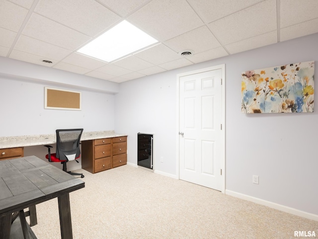 carpeted home office with a drop ceiling, visible vents, baseboards, and built in study area