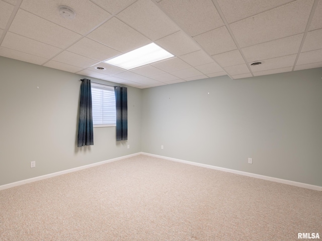 carpeted empty room featuring a paneled ceiling and baseboards