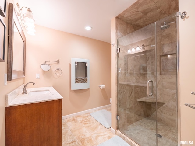 bathroom with vanity, toilet, baseboards, and a stall shower