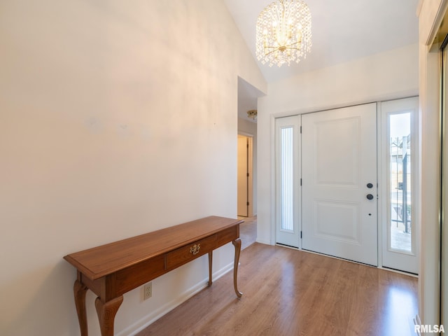 foyer featuring a notable chandelier, lofted ceiling, and light wood-style floors