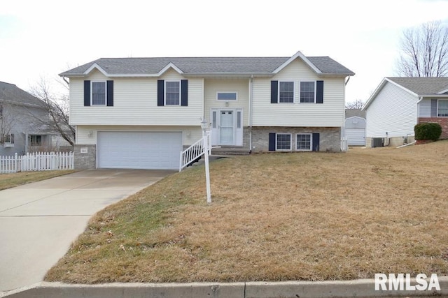 bi-level home featuring brick siding, driveway, a front yard, and fence