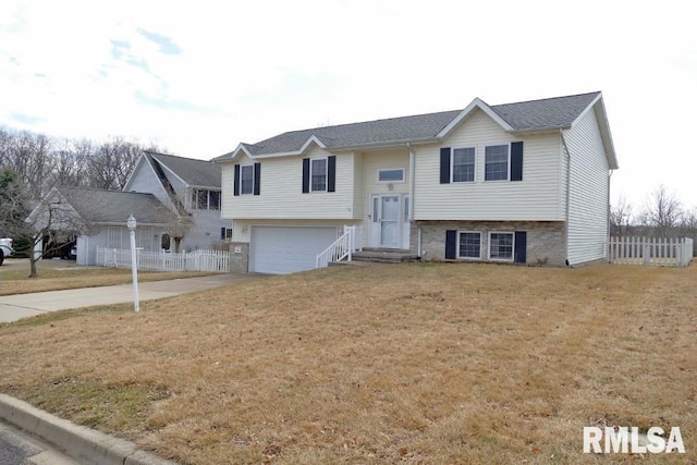 raised ranch with a front lawn, fence, a garage, and driveway