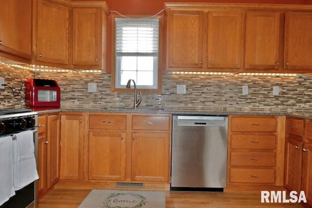 kitchen with light stone countertops, visible vents, a sink, decorative backsplash, and stainless steel appliances