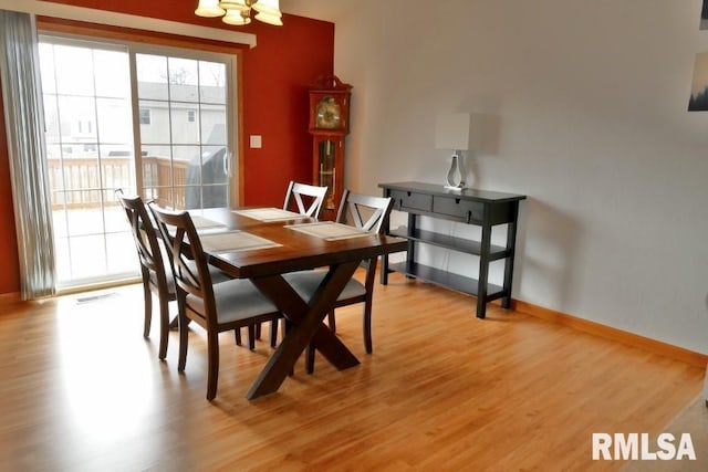 dining room with baseboards, a chandelier, and light wood finished floors