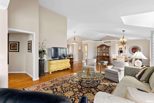 living room featuring an inviting chandelier, lofted ceiling with skylight, wood finished floors, and baseboards