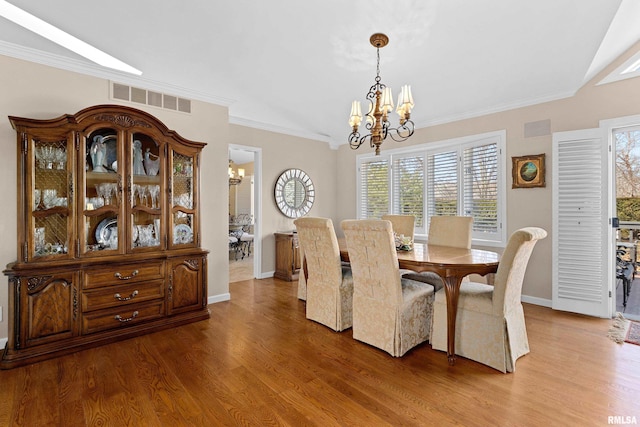 dining room featuring an inviting chandelier, crown molding, visible vents, and light wood finished floors