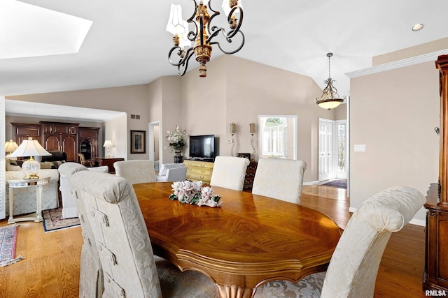 dining area featuring baseboards, light wood-style floors, an inviting chandelier, and vaulted ceiling