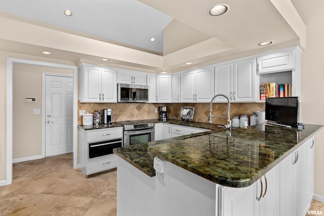 kitchen featuring white cabinetry, appliances with stainless steel finishes, dark stone counters, and a peninsula