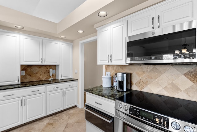 kitchen featuring a warming drawer, tasteful backsplash, dark stone counters, appliances with stainless steel finishes, and white cabinets