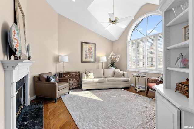 living room featuring baseboards, a premium fireplace, vaulted ceiling, wood finished floors, and a ceiling fan